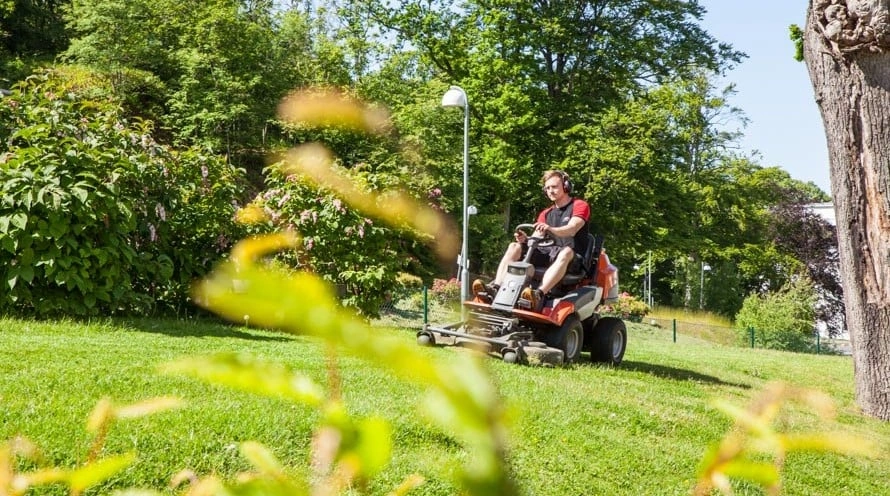 En fastighetsskötare klipper gräs - en del av fastighetsskötsel av trädgård och utemiljö